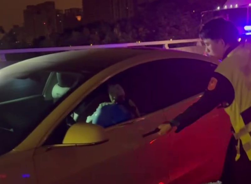 一輛白色未懸掛車牌的特斯拉電動車停在國道上，警方到場查看發現，該名男子當時抱著一顆藍色氣球正在吸食，且神情恍惚。圖／民眾提供